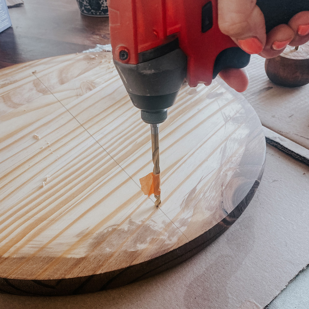 A person drilling holes to a round board. A person drilling holes to a round board.