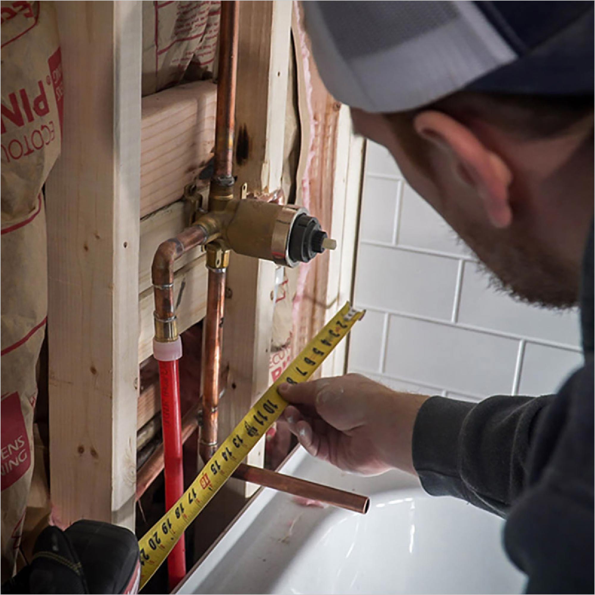 A Pro makes measurements for a plumbing rough-in.