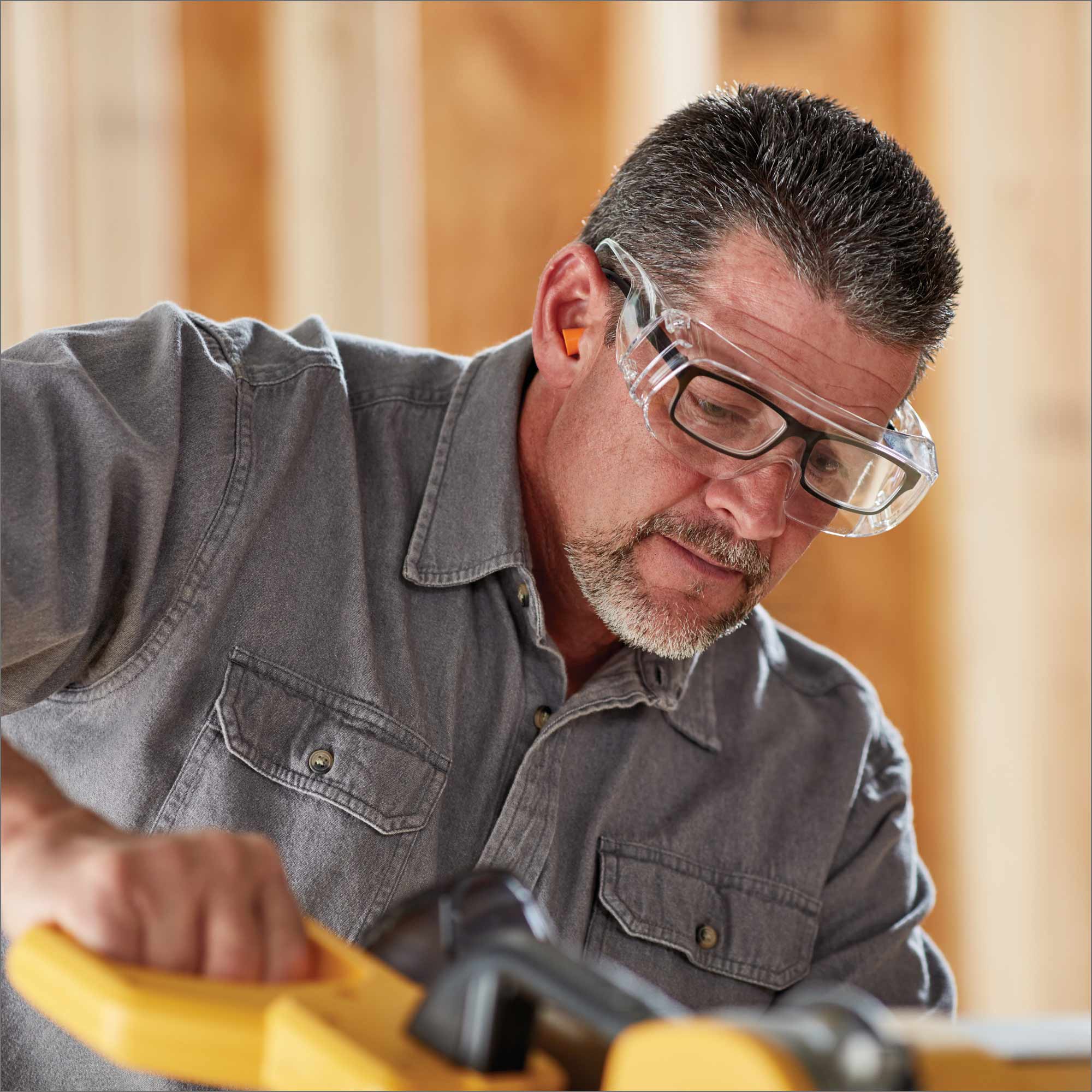 A worker wears safety goggles over his glasses.