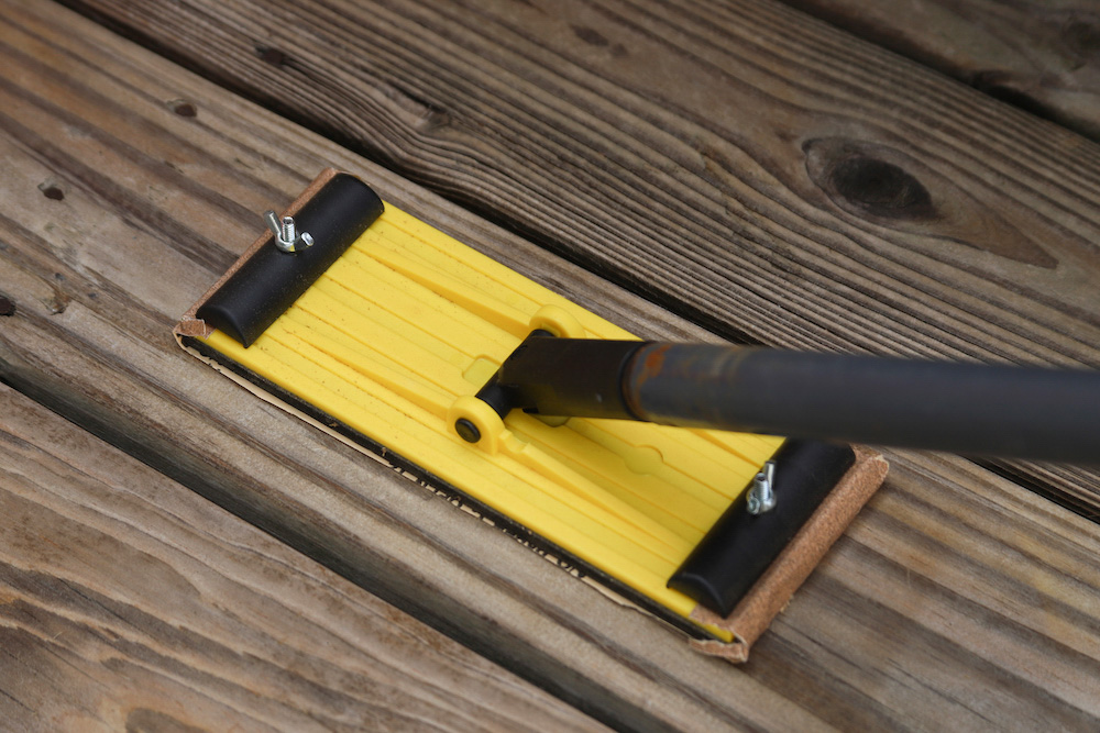 A deck board is sanded with a pole sander. A deck board is sanded with a pole sander.