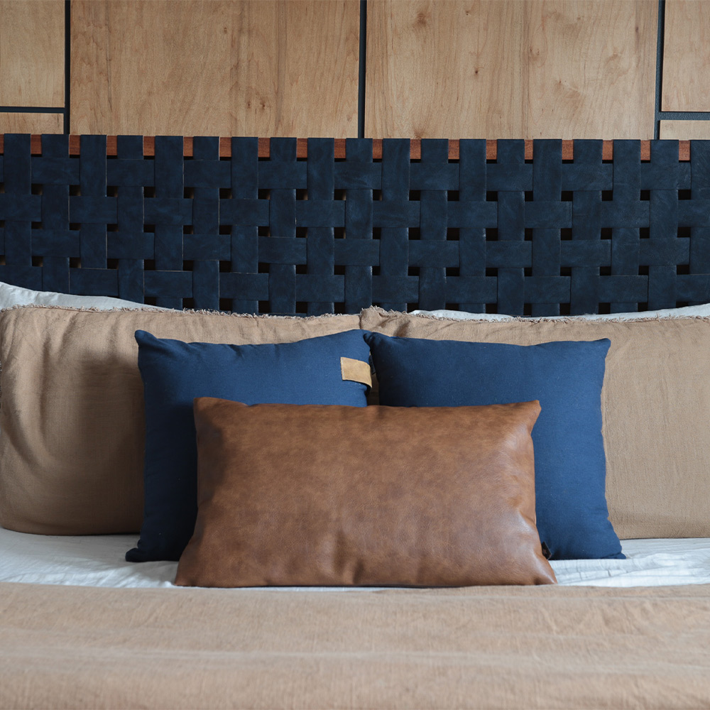 Head of bed with leather pillows in front of completed headboard.