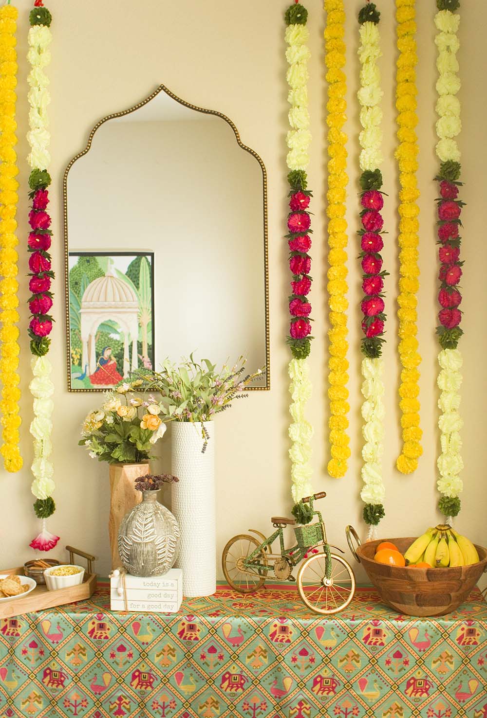 A mirror and wall flowers with a table.