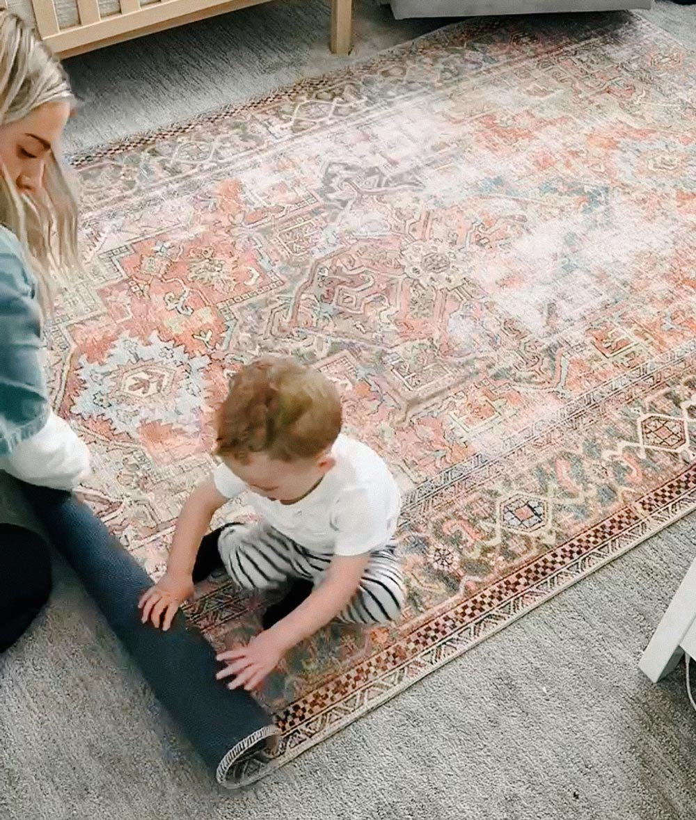 A person and child rolling out a rug.