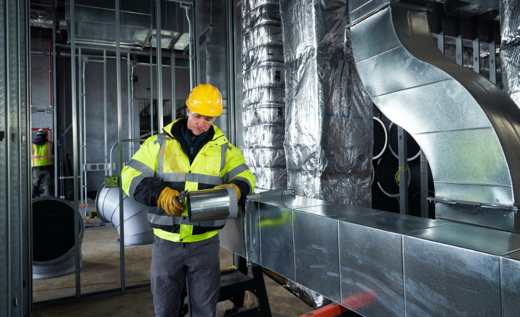 A technician performs maintenance on HVAC ductwork.