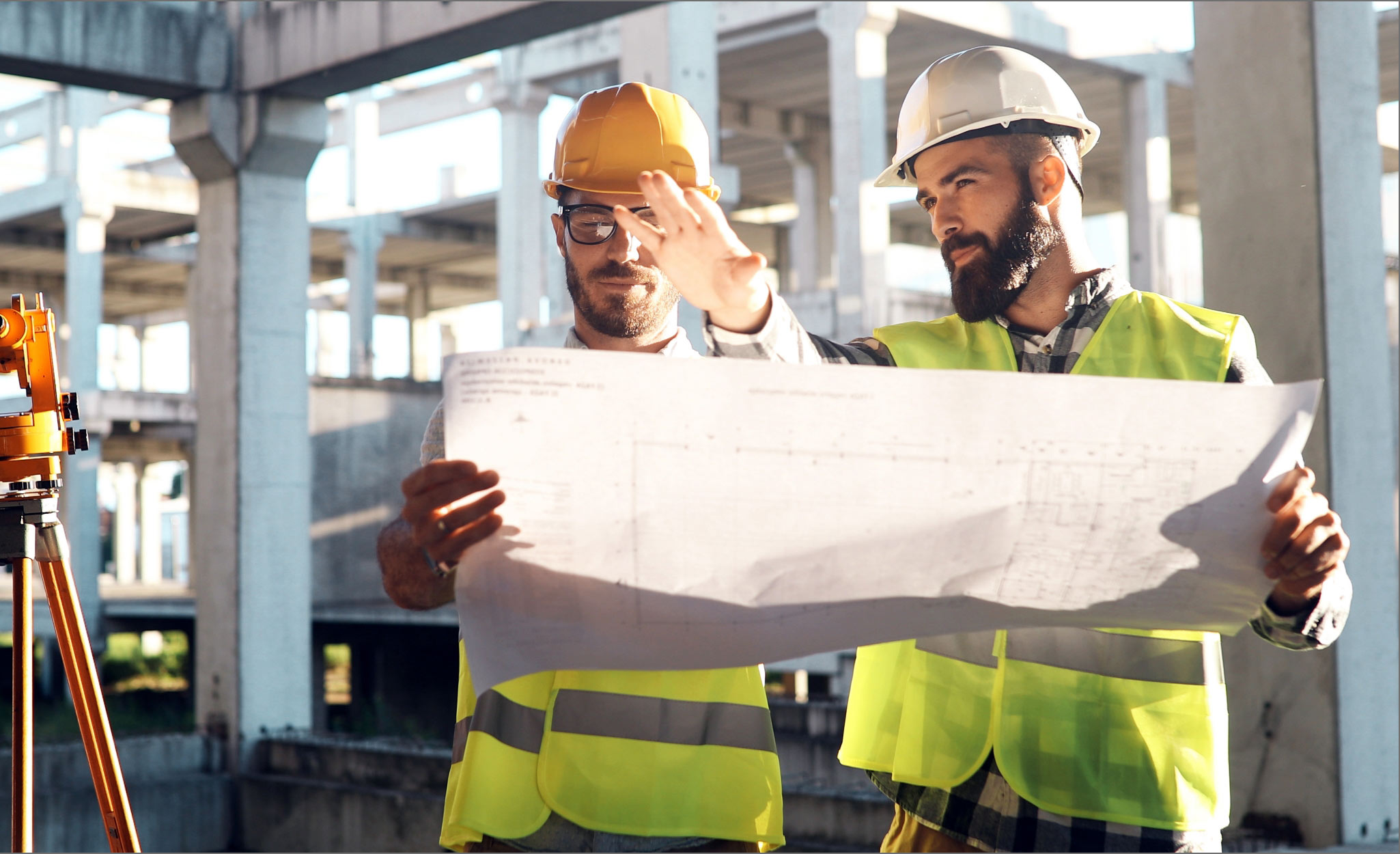 Workers review building plans on a construction site.