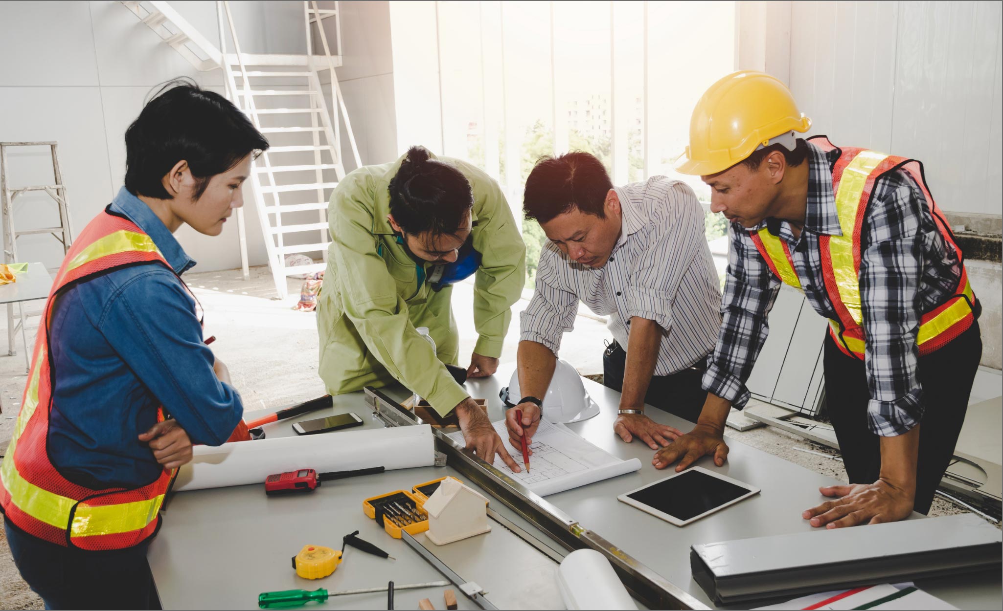 A group of workers review plans on a work site.