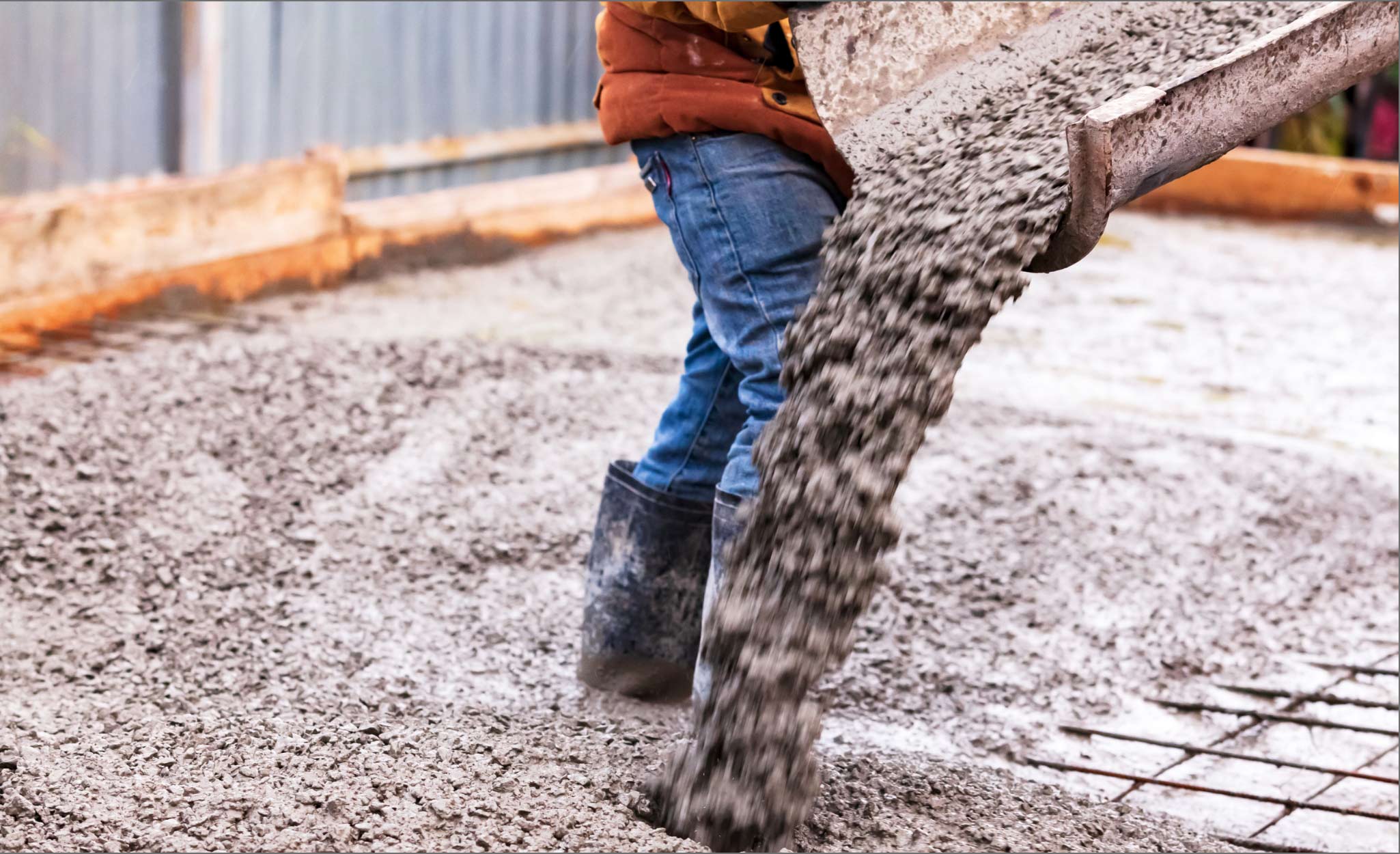 Wet cement pours from a cement mixer chute.