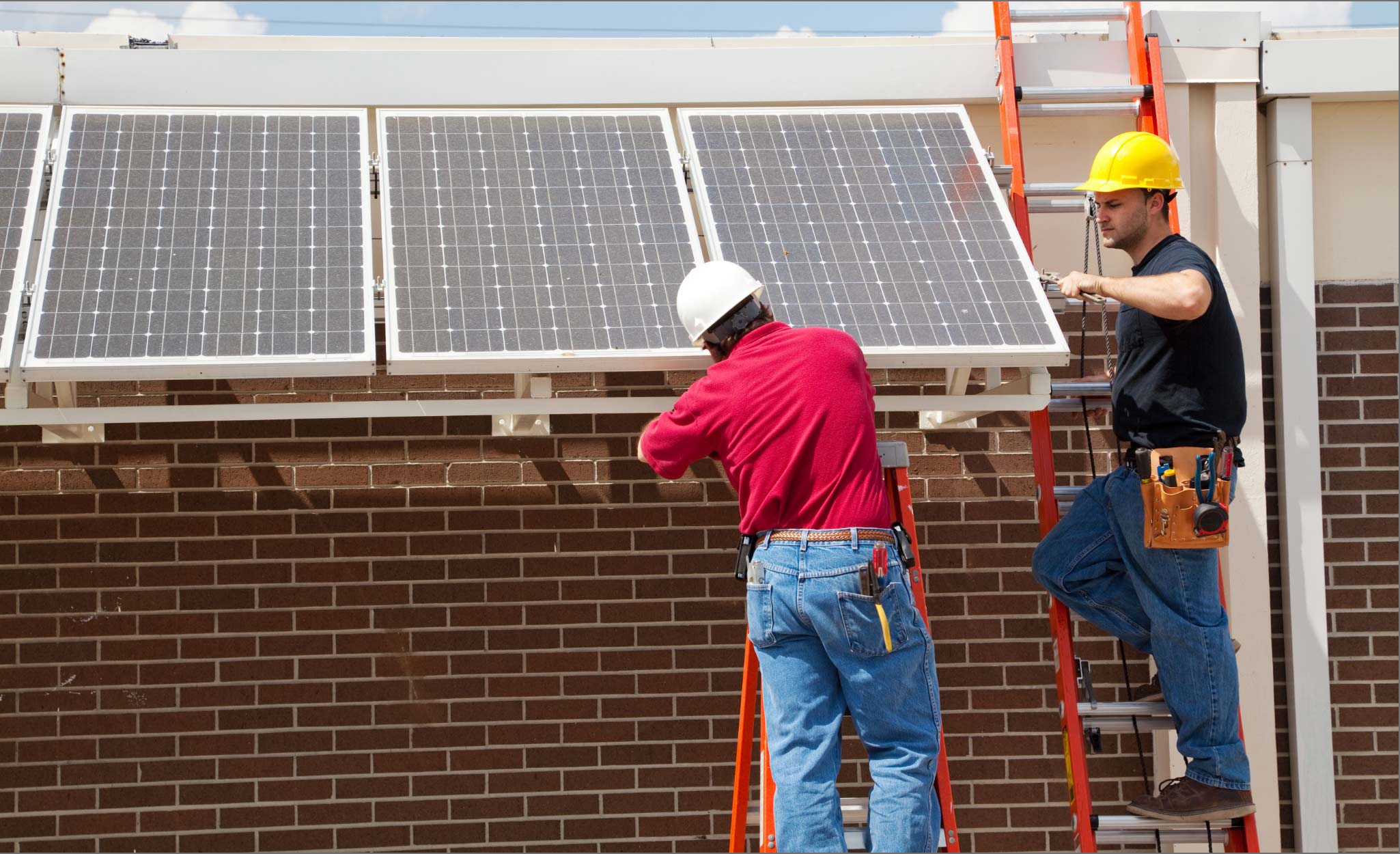 Workers install solar panels on a roof.