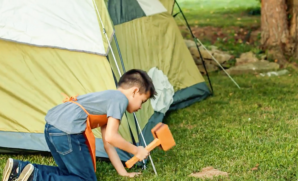 Kid hammers in the sides of the tent.