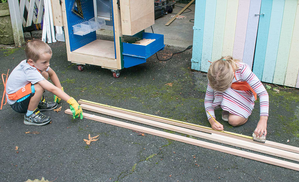 Two children help lay out lumber. 