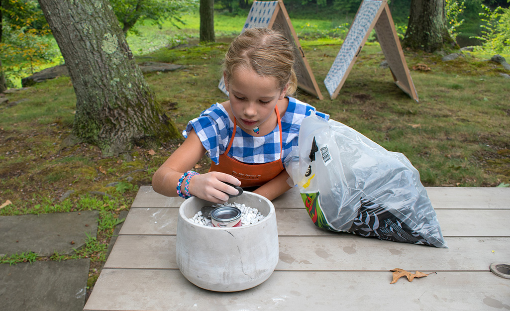 A little girl puts together a DIY fire pit.