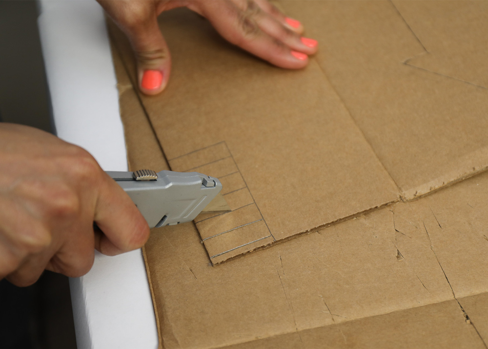 Shot of person cutting shape of fence through cardboard