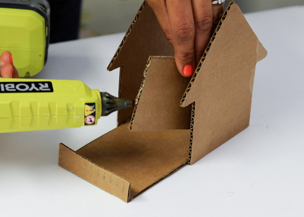 Shot of person applying hot glue to the edge of cardboard piece