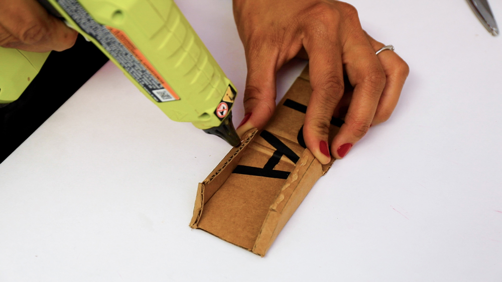 hands folding a piece of cardboard while hot glueing an edge