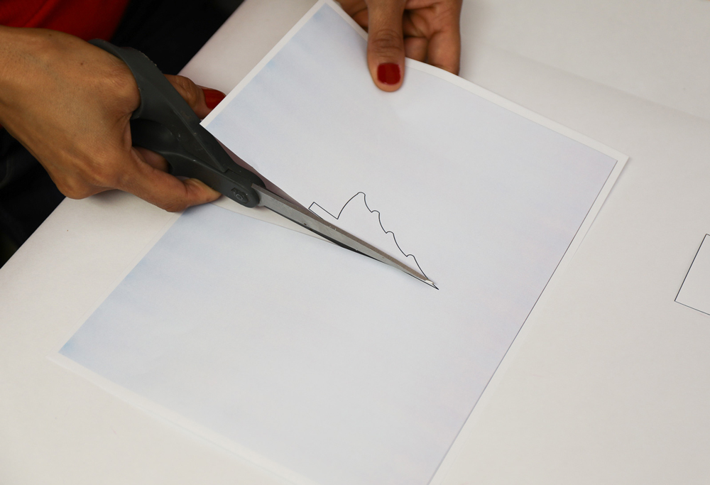 a woman’s hands cutting out a paper tree template with scissors