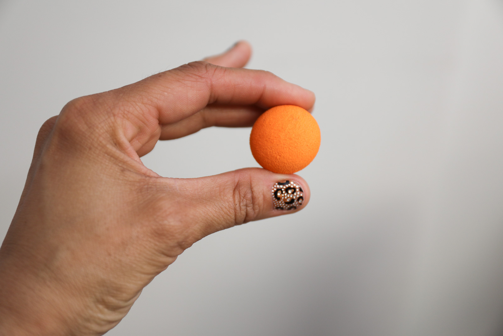 A hand holding up a small orange ball