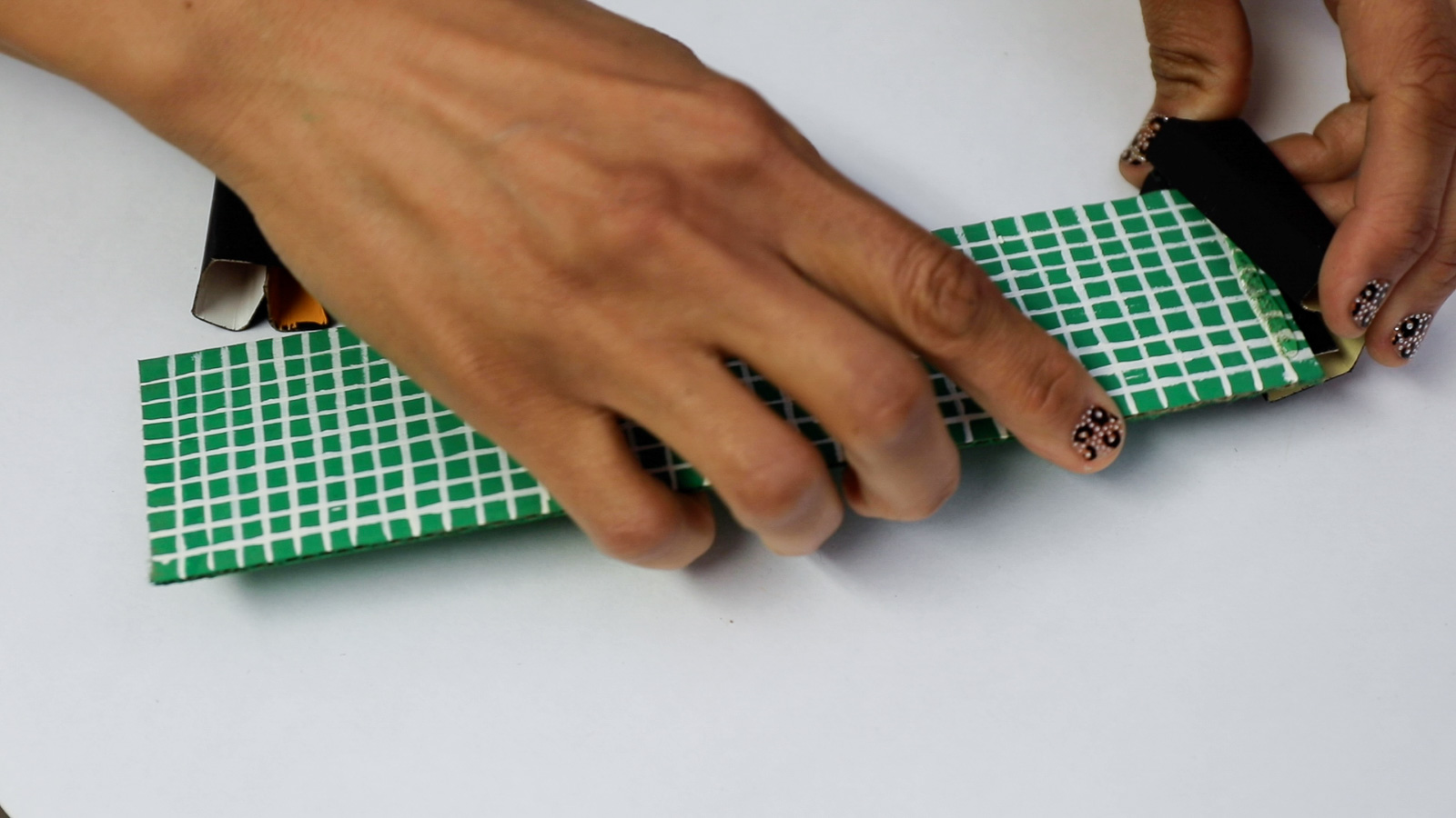 A person adding black painted ends to a DIY green net 