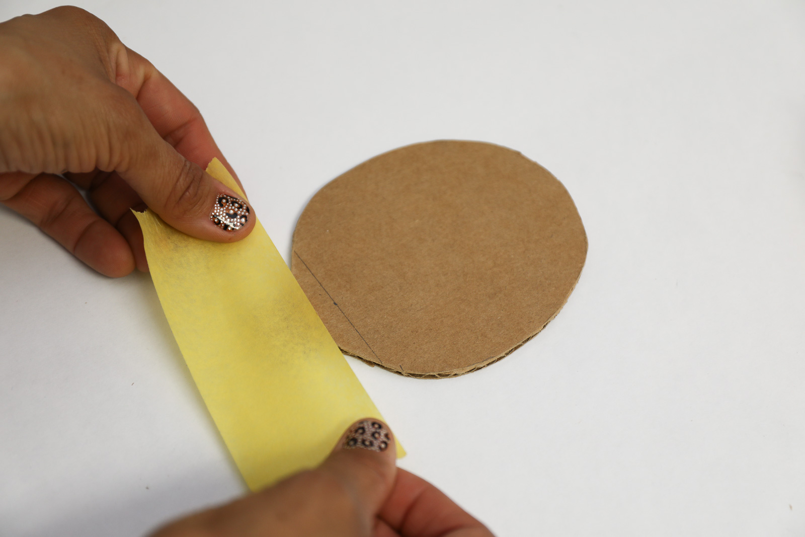 A person applying yellow tape to a piece of cutout cardboard