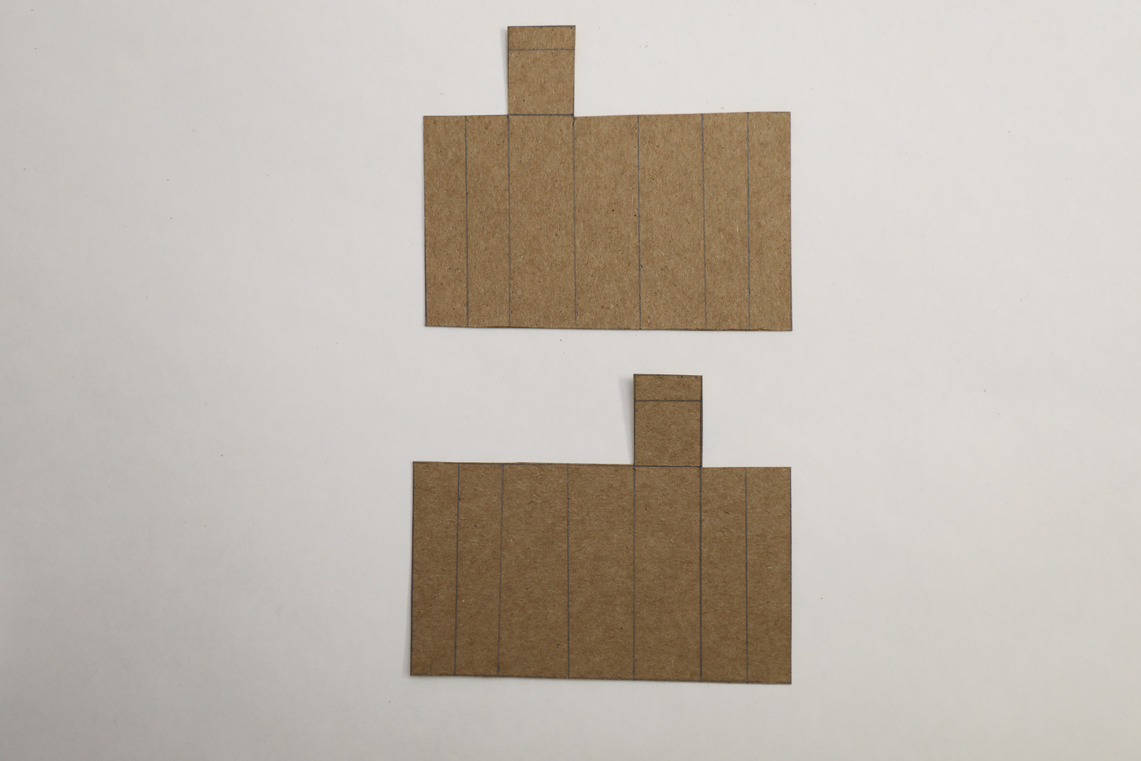 Two rectangle card board cut outs placed on a white table top 
