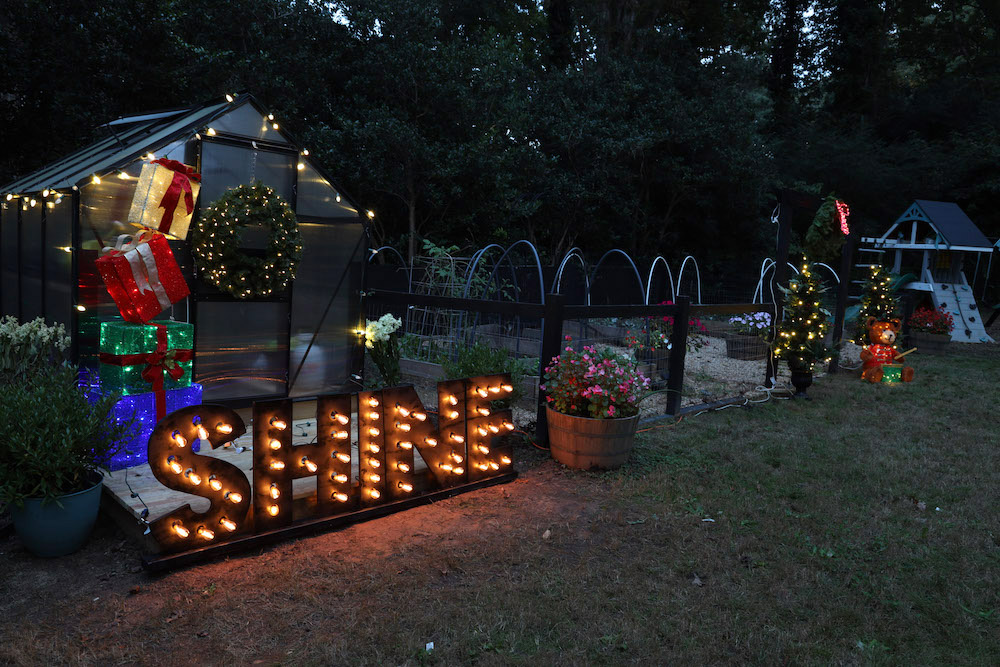 Greenhouse and garden styled with lights, trees, gift box set, marquee sign and pre-lit wreath
