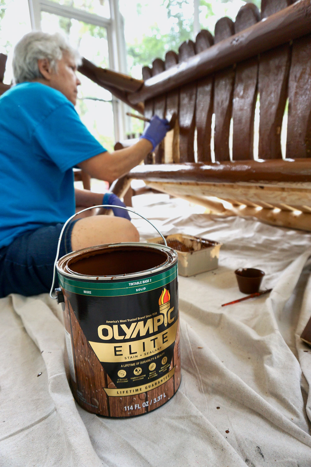 A woman sits on the ground to stain wooden furniture. A woman sits on the ground to stain wooden furniture.