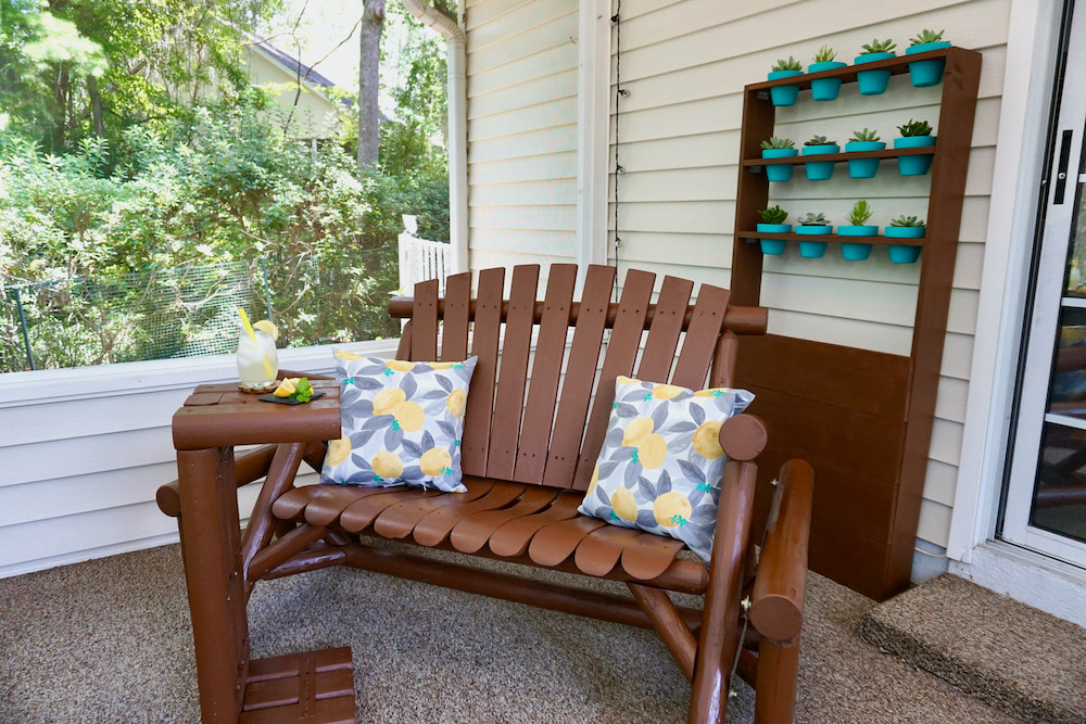 A wooden chair stained brown decorated with lemon themed pillows. A wooden chair stained brown decorated with lemon themed pillows.