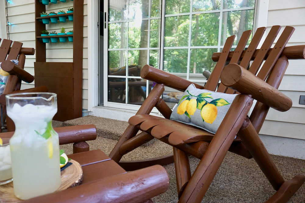 A carpeted porch decorated with brown stained wooden furniture and lemon themed pillows. A carpeted porch decorated with brown stained wooden furniture and lemon themed pillows.