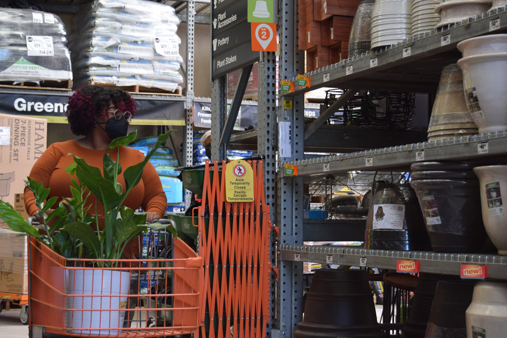 A woman pushing a cart with plants at Home Depot.