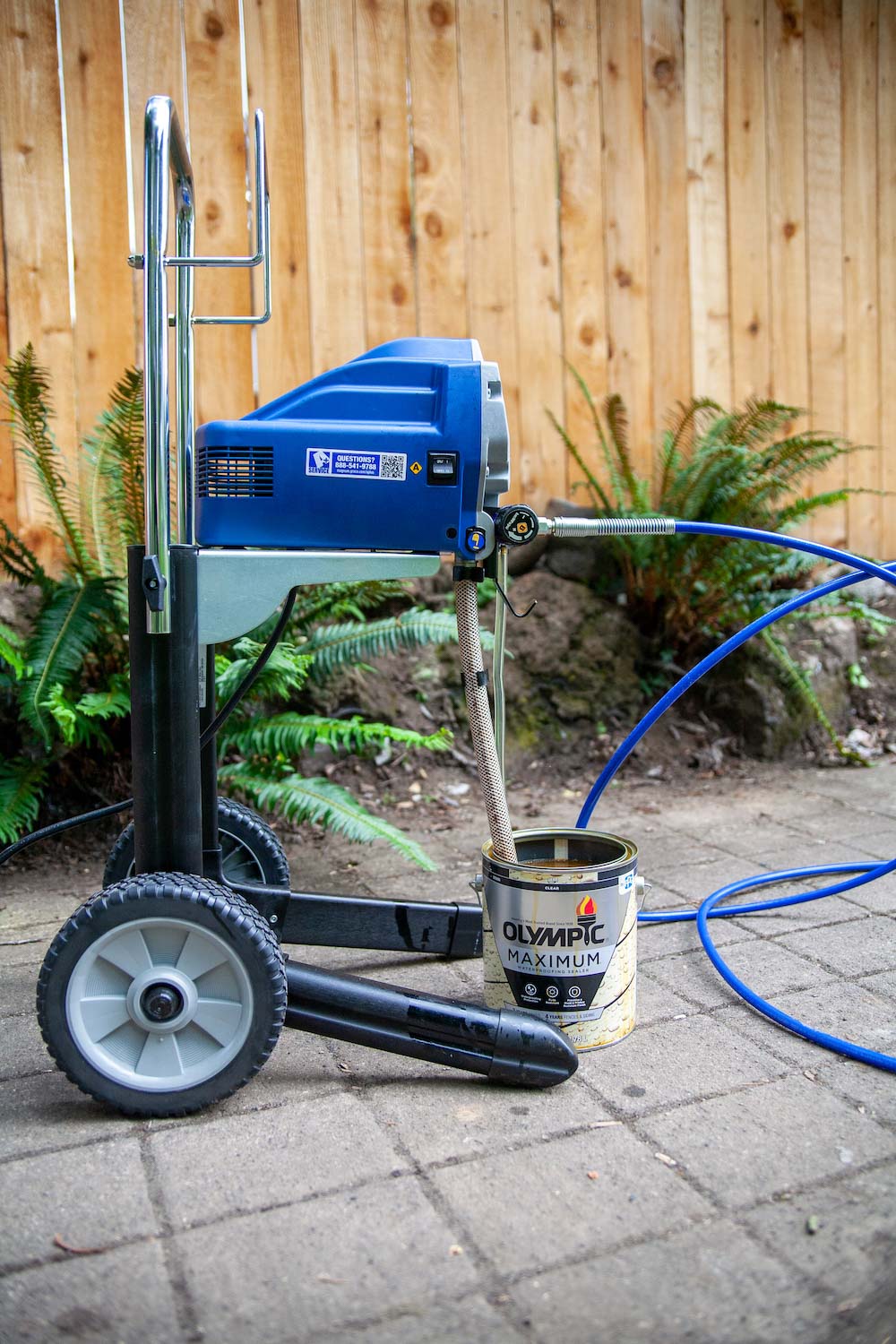 An airless sprayer and a can of Olympic Maximum Waterproofing Sealer. An airless sprayer and a can of Olympic Maximum Waterproofing Sealer.