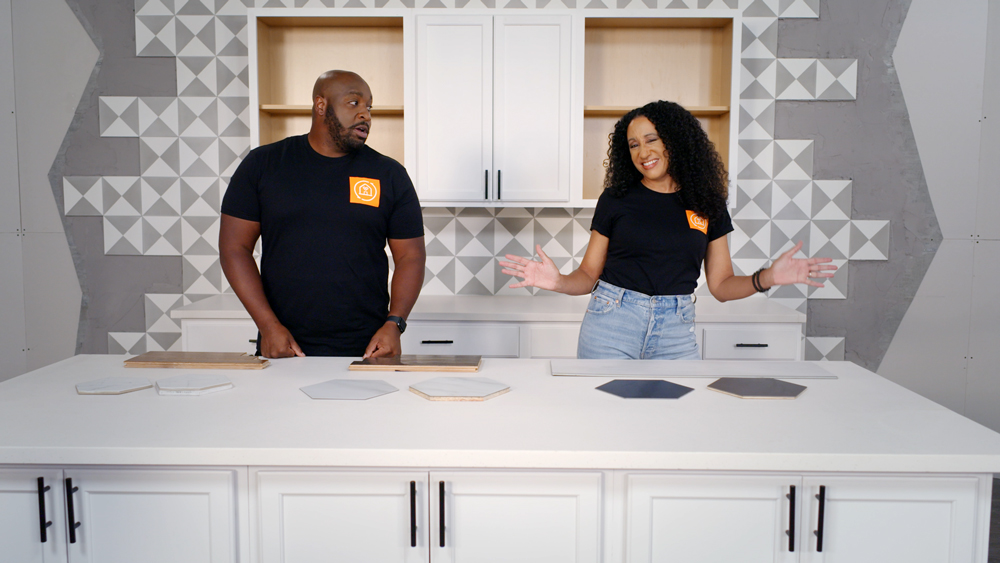 A man and a woman standing at a counter with wood pieces on the countertop A man and a woman standing at a counter with wood pieces on the countertop