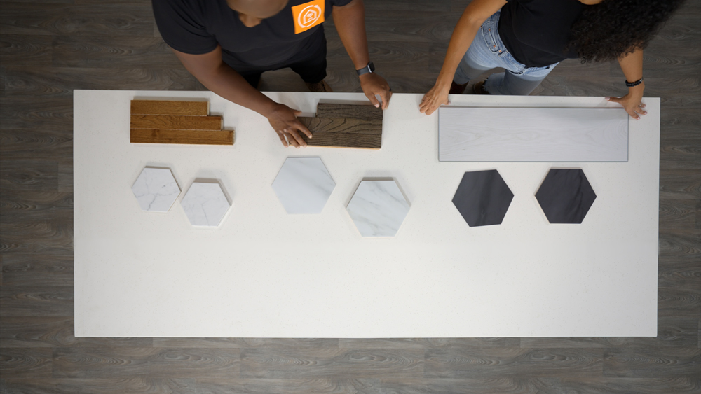 A bird’s eye view of a man and a woman standing at a counter with pieces of floor materials A bird’s eye view of a man and a woman standing at a counter with pieces of floor materials