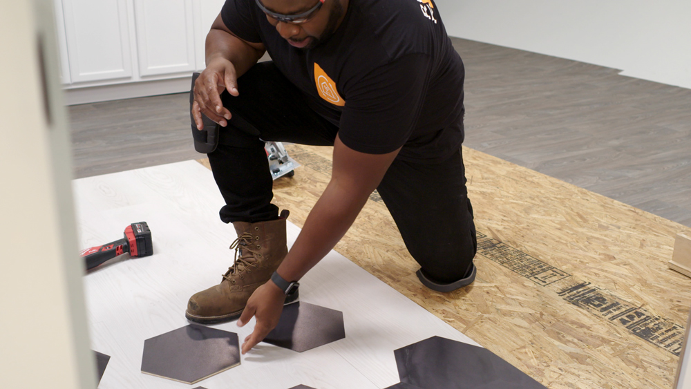 Man kneeling on floor laying wooden hexagonal pieces Man kneeling on floor laying wooden hexagonal pieces