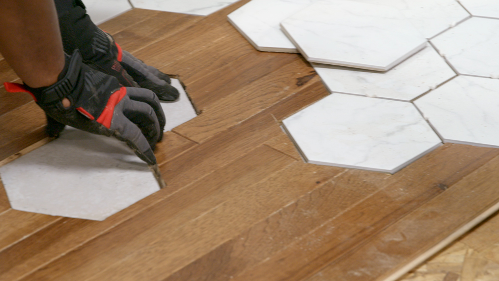Hands with gloves working with wooden flooring pieces Hands with gloves working with wooden flooring pieces