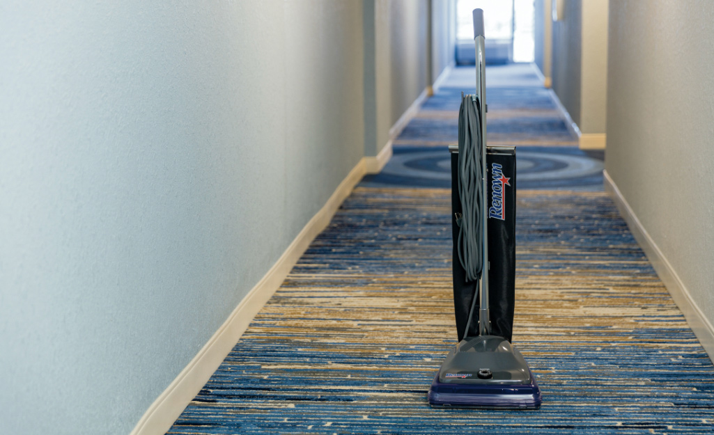 A vacuum sits on commercial carpet