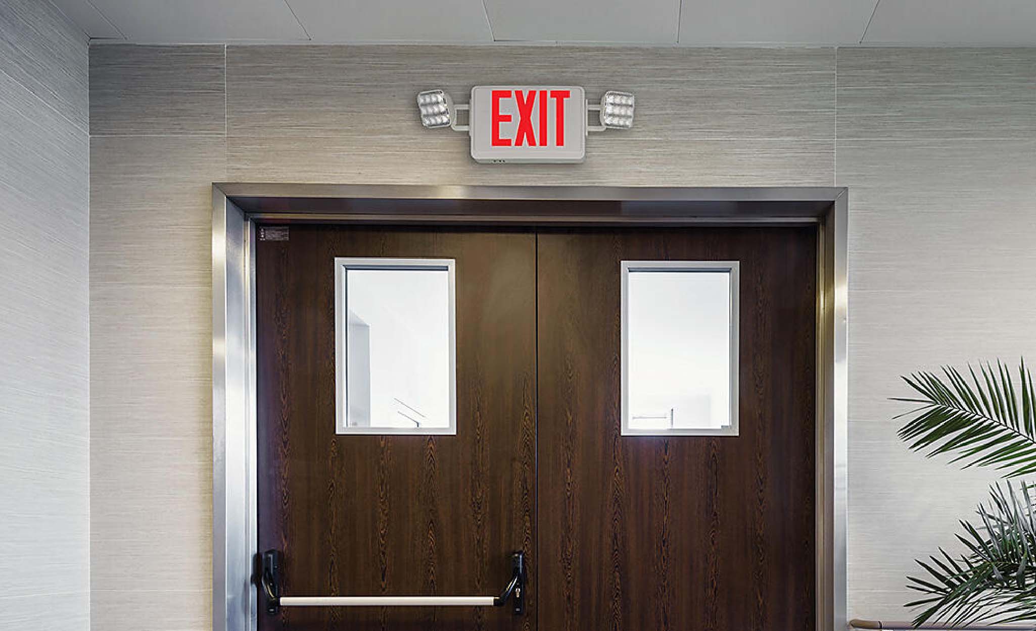 An exit sign and lights over a pair of doors.