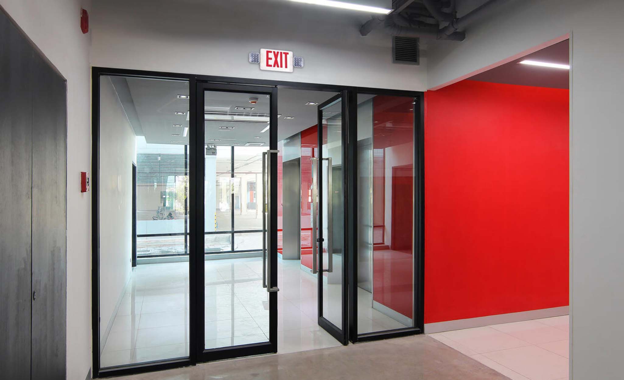 An emergency exit sign above sliding glass doors.