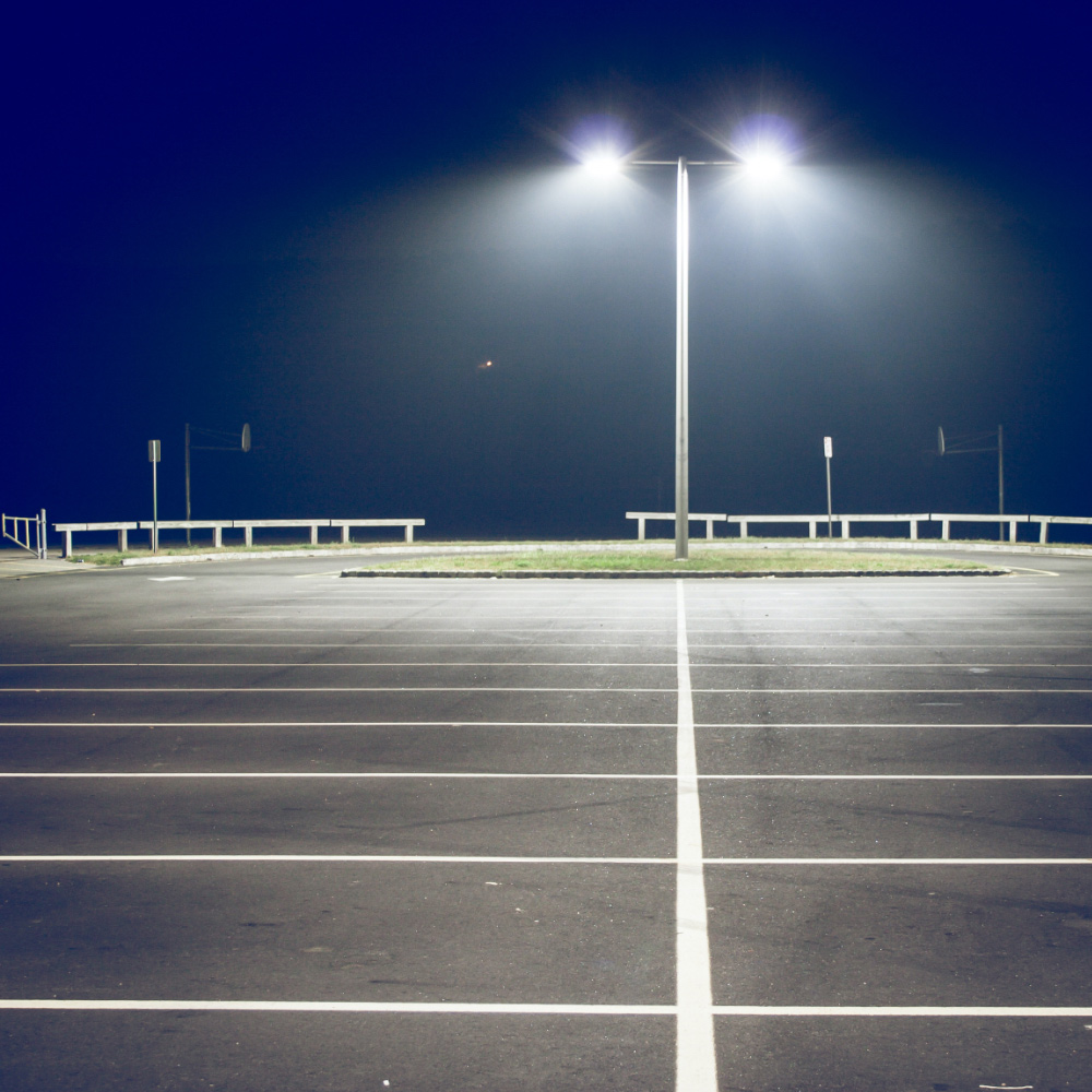 Pole lighting illuminates a parking lot at night.