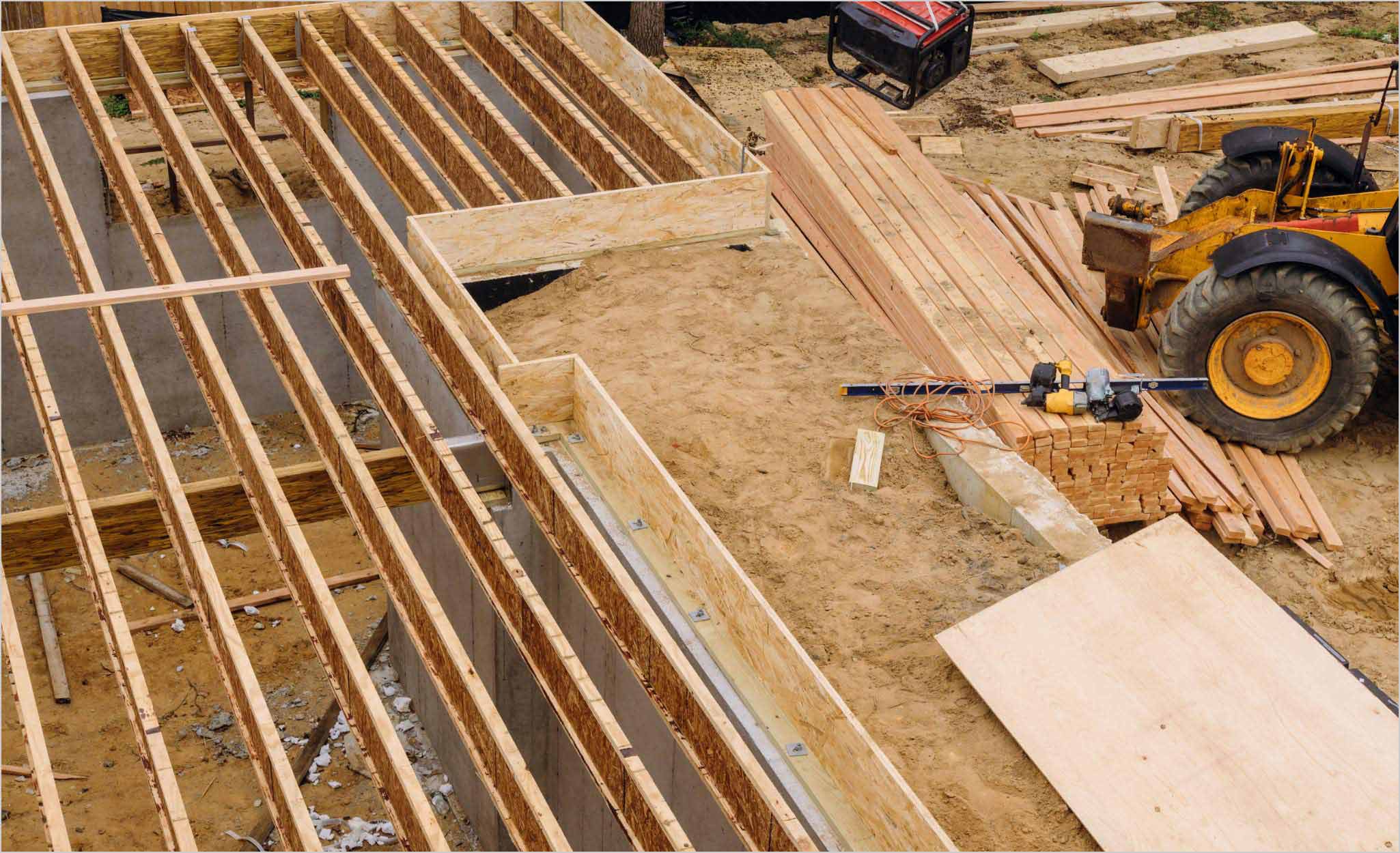 Builders frame the basement joists and subfloor of a house.