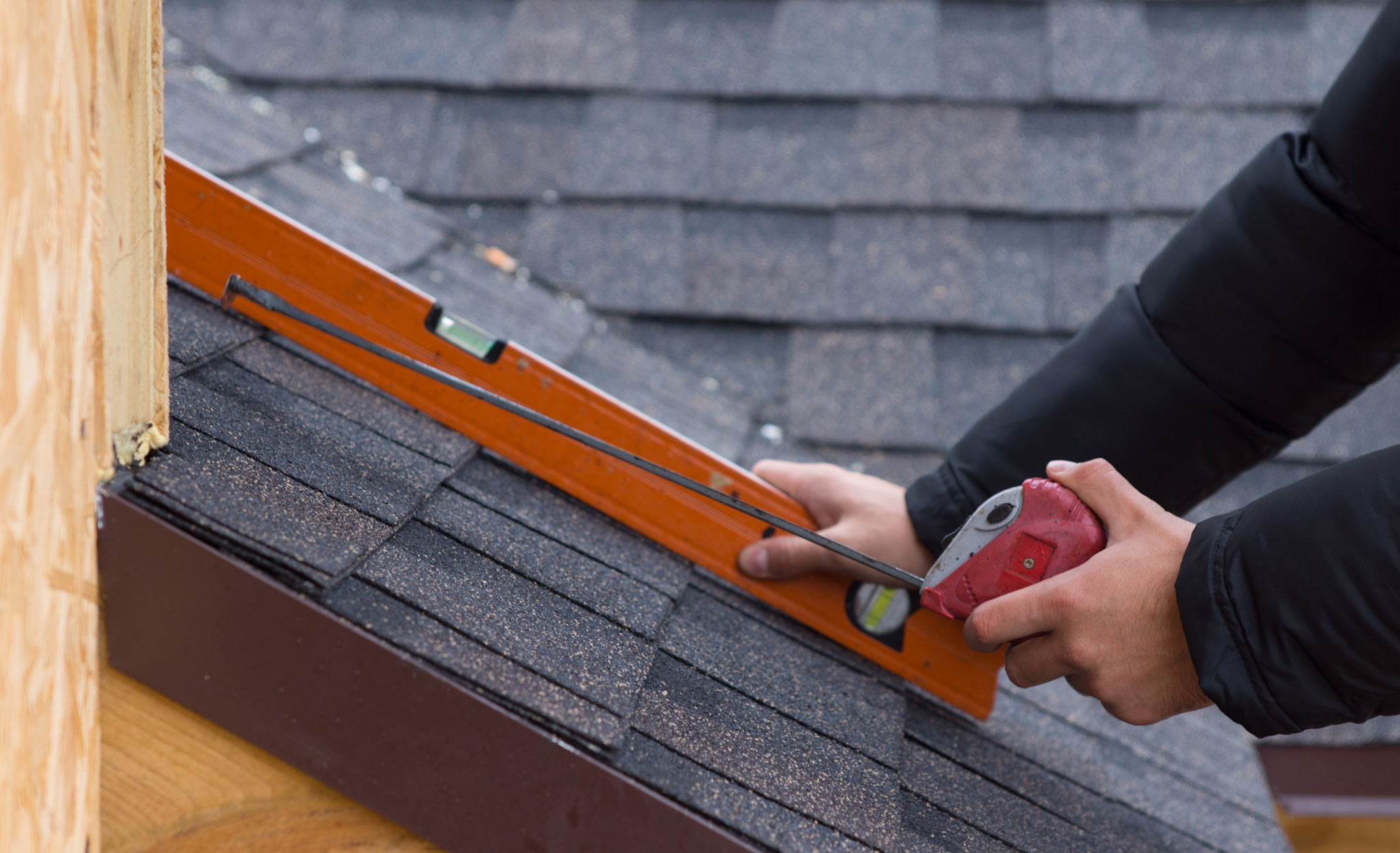 A Pro calculates roof pitch with a level and a tape measure.