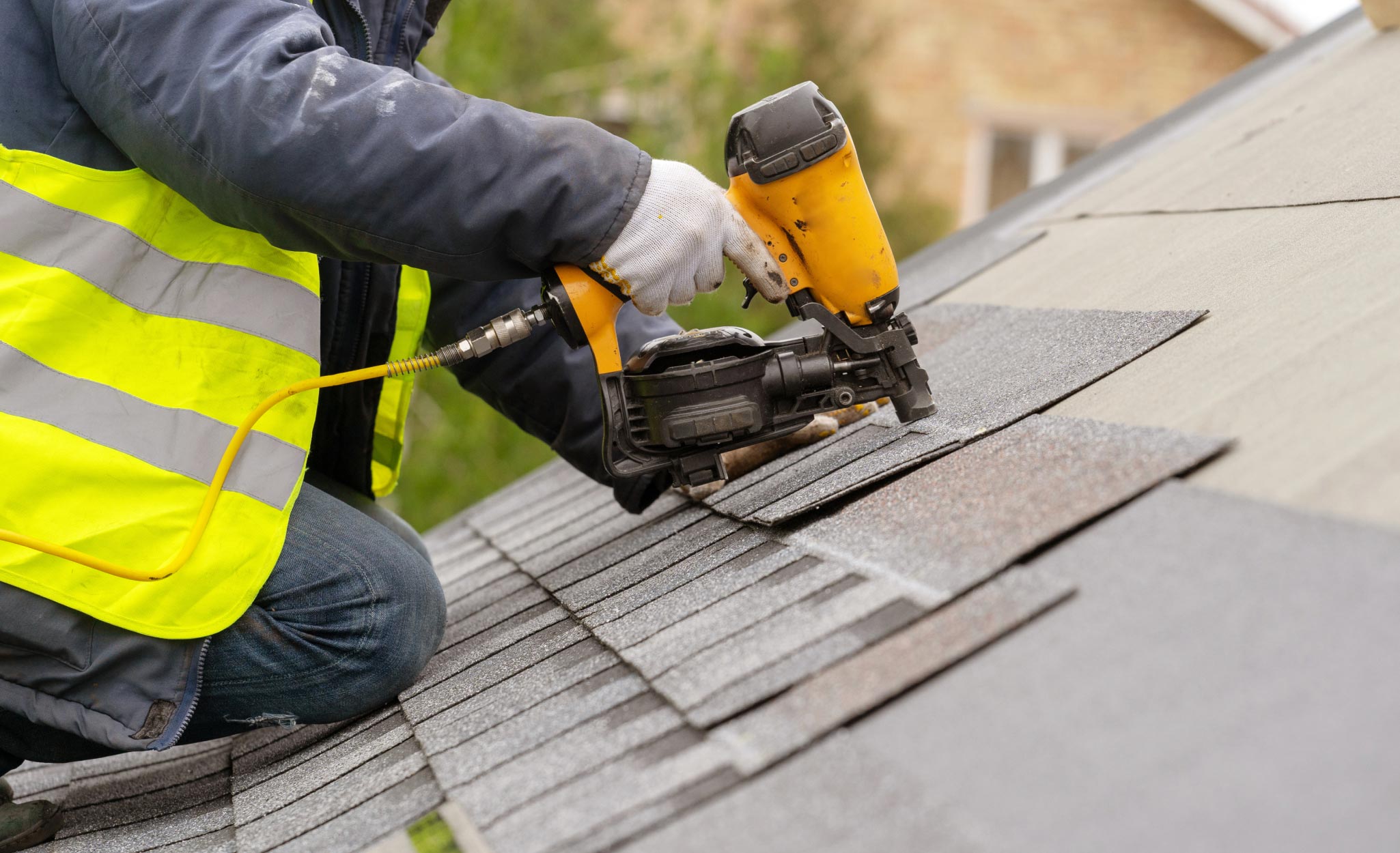 A Pro replaces shingles on the roof of a house.