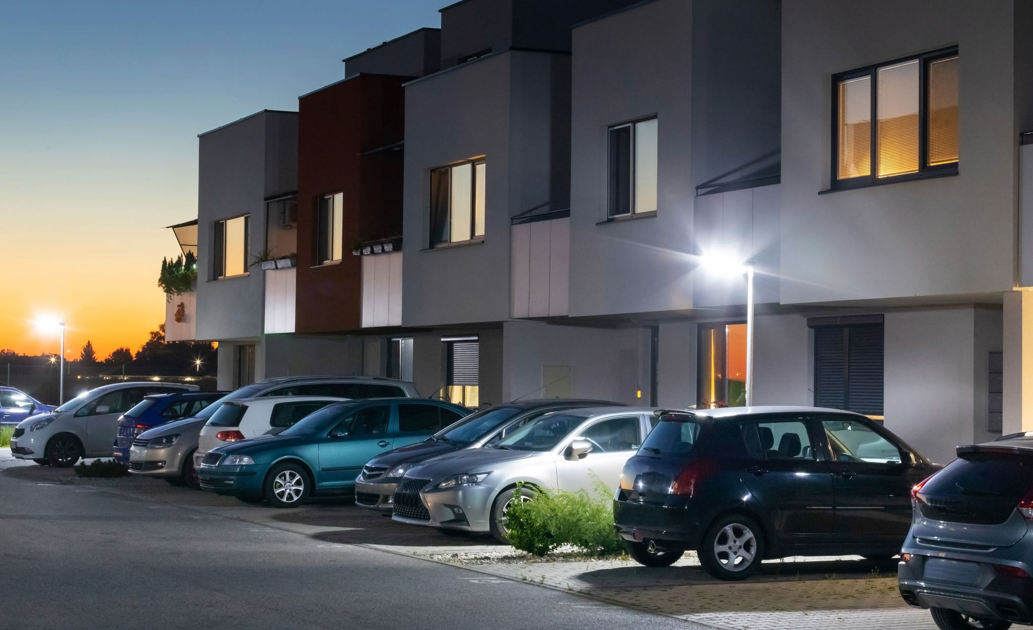 Security lights illuminate apartment parking spaces.