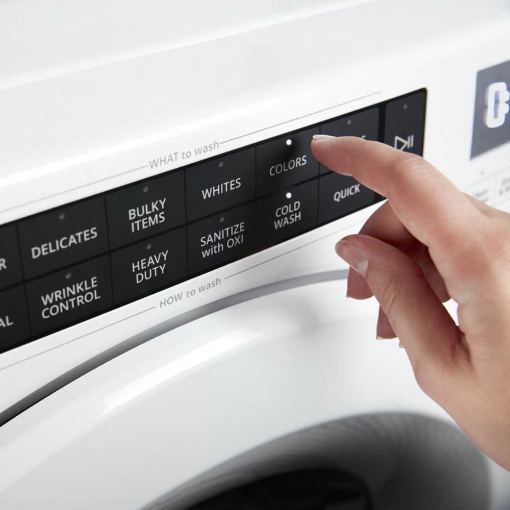 A person uses a control panel on a Whirlpool washing machine.