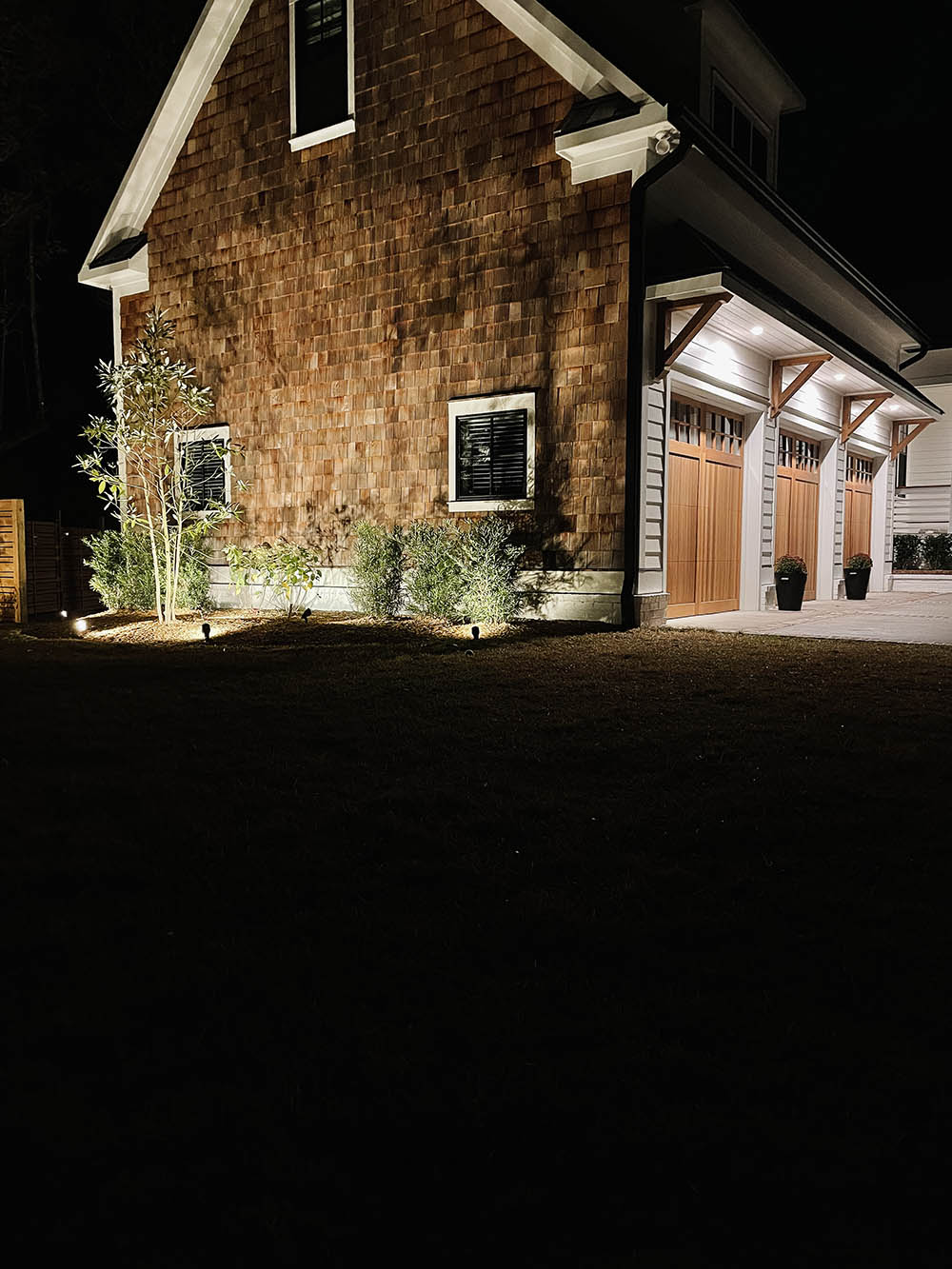 A house at night being lit by small outdoor lights.