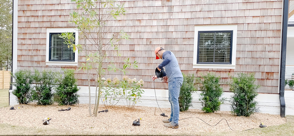 A man laying out wires to connect his outdoor lights.
