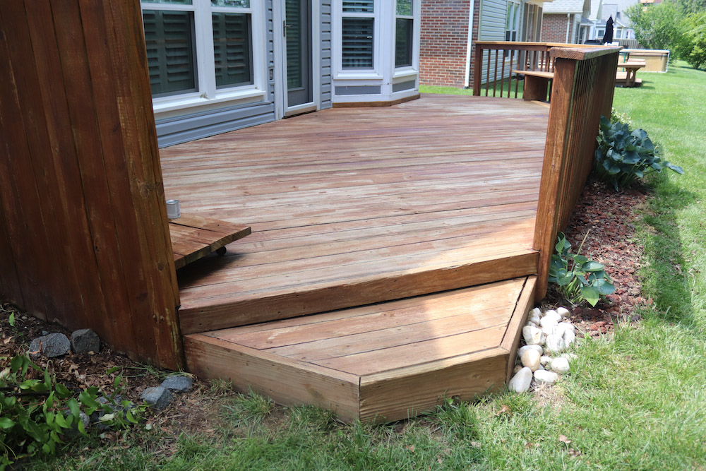A wooden deck off the back of a home.