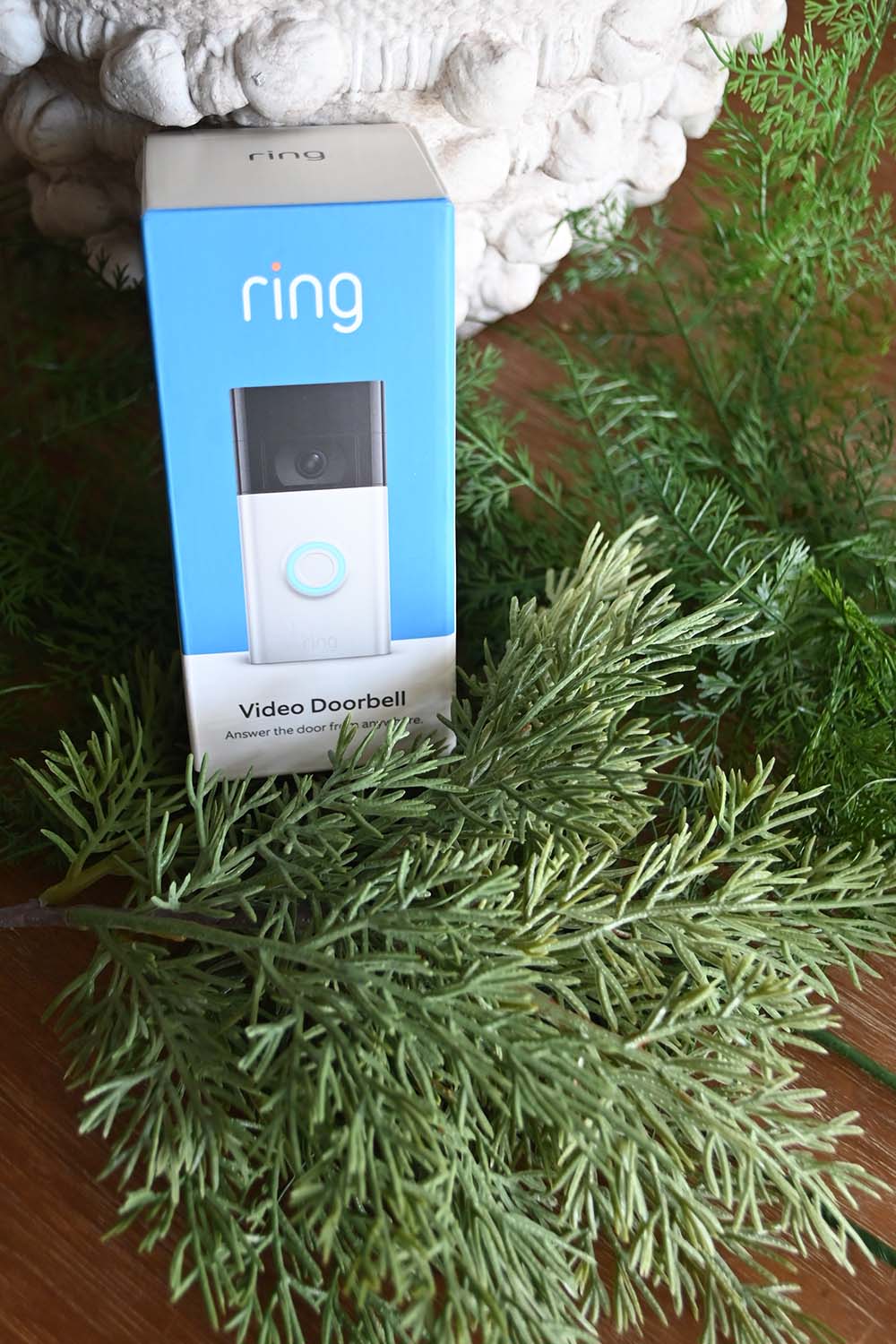 A Ring Video Doorbell Camera sitting atop pine tree branches.