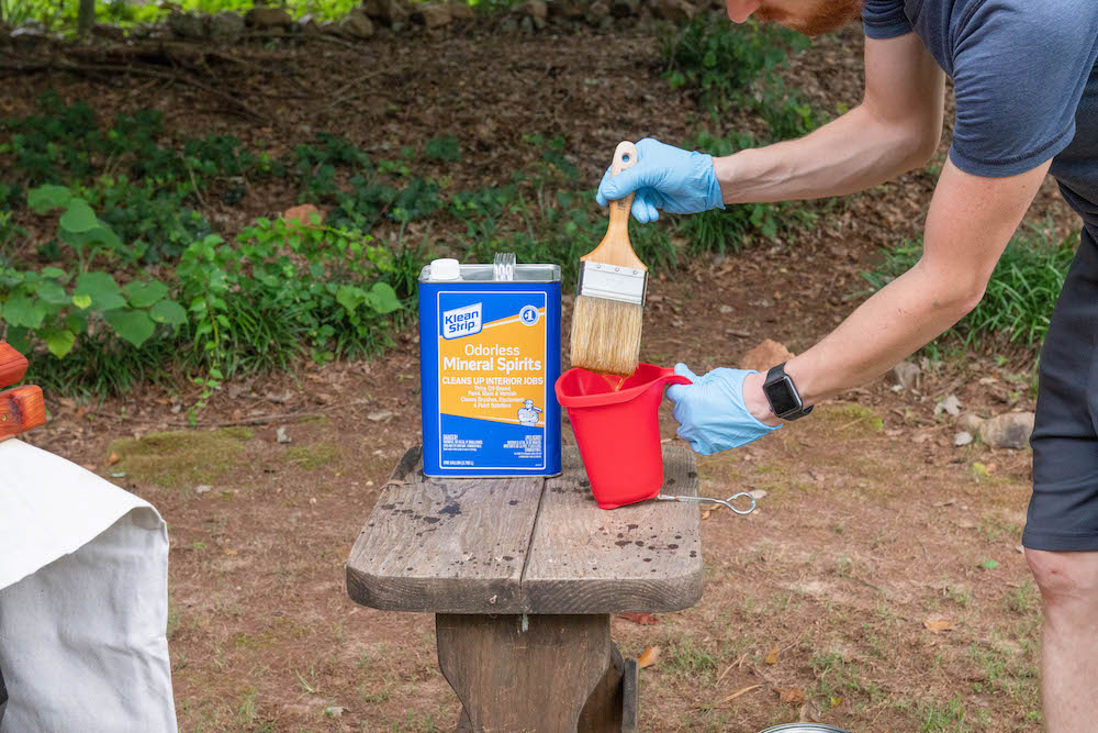 A man cleaning a paint brush with mineral spirits.