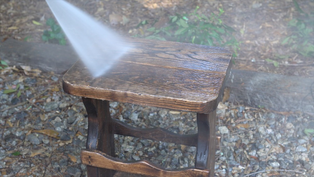A wooden side table is washed off with water.