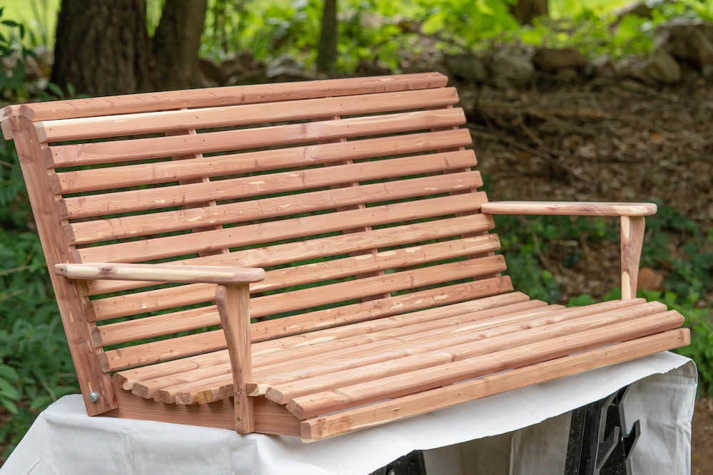 A wooden exterior swing sitting on a drop cloth.