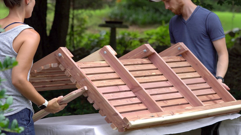 A woman and man flipping over an exterior wood swing.